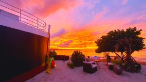 um pôr do sol na praia com cadeiras e árvores em Bluemare EcoHotel Frente a la playa Ensendada em Punta Rucia