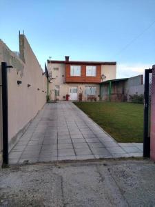 une allée menant à une maison avec une clôture dans l'établissement Casona confortable y cálida con hermoso jardín, à Río Gallegos