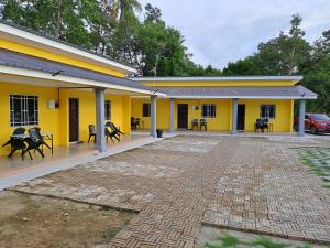 a yellow building with tables and chairs on a patio at Room/Homestay NazaDja in Sungai Besar