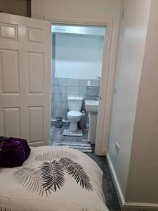 a bathroom with a bed and a bathroom with a toilet at Impeccable 4-Bed House Near Manchester City Centre in Manchester