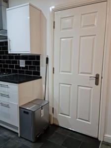 a kitchen with a white door and a refrigerator at Impeccable 4-Bed House Near Manchester City Centre in Manchester