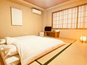 a bedroom with a large white bed and a window at Hotel Yu-shu in Osaka