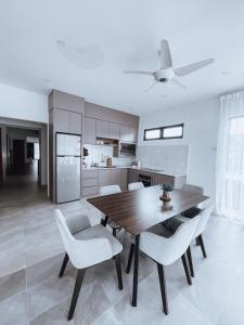 eine Küche mit einem Holztisch und weißen Stühlen in der Unterkunft Nur Villa Sg Soi in Kuantan