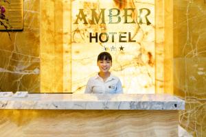 a woman standing behind a counter at a hotel at Amber Hotel managed by HT in Nha Trang