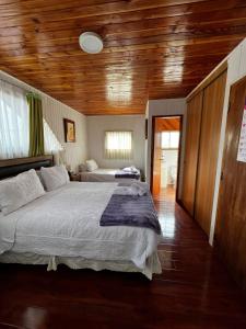 ein Schlafzimmer mit einem großen Bett und einer Holzdecke in der Unterkunft Hostal Katemu in Villarrica