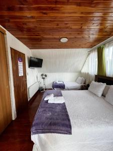 a bedroom with a large bed with a wooden ceiling at Hostal Katemu in Villarrica