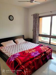 - une chambre avec un lit doté d'une couette colorée et d'une fenêtre dans l'établissement 2BHK Lake View Apartment, à Lavasa