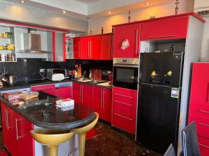 een keuken met rode kasten en een zwarte koelkast bij Sunterra in Sharm El Sheikh