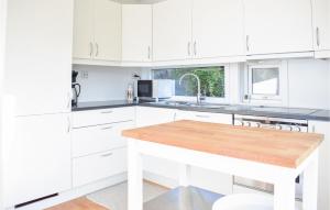 a white kitchen with white cabinets and a wooden counter top at Awesome Home In Jrpeland With 4 Bedrooms in Jørpeland