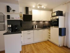 a kitchen with white cabinets and black counter tops at Upland Apartments - Fewo Zeitgeist (inkl. MeineCardPlus) in Willingen