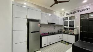 uma cozinha com armários brancos e um frigorífico de aço inoxidável em Aurora Homes em Marang