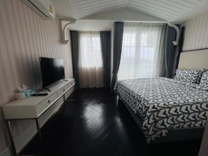 1 dormitorio con 1 cama y escritorio con TV en FLORIDA GARDEN PATTAYA, en Na Jomtien