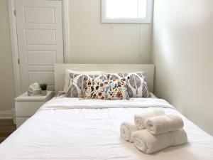 Un dormitorio con una cama blanca con toallas. en Beautiful Walk out Basement Apartment in Pickering near Beach en Pickering