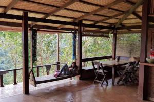 a girl laying on a bed in a room with a table at Greenleas, Cottage, Swimming Pool and Log Fire in Mae Chan