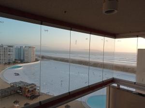 a room with a view of the ocean and a swimming pool at Departamentos Laguna del mar in La Serena