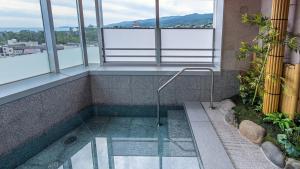 a jacuzzi tub in a building with windows at Tenseien Odawara Station Annex in Odawara
