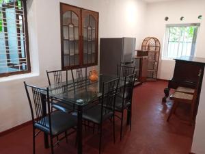 ein Esszimmer mit einem Tisch und Stühlen sowie einem Kühlschrank in der Unterkunft Villa Arunodaya in Hikkaduwa
