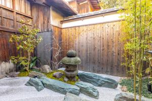 a zen garden with a stone statue in front of a fence at GION KAWASEMI in Kyoto