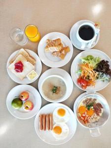 a table with plates of food and a cup of coffee at Mayflower Grand Hotel Korat in Nakhon Ratchasima