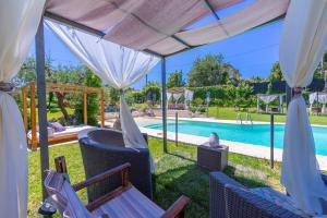 een villa met een zwembad met stoelen en een luifel bij La Casa Fra gli Ulivi - Piscina e natura, relax vicino al mare tra Cinque Terre e Toscana in Monte Marcello