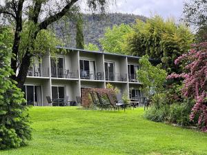 a building with chairs and tables in a yard at Riverbank Park MOTEL in Bright