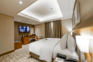 Pokój hotelowy z białym łóżkiem i telewizorem w obiekcie Boudl Al Sulimanyah w Rijadzie