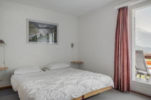 a white bedroom with a bed and a window at Kirschstein OG in Fiesch