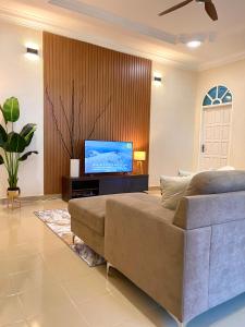a living room with a couch and a flat screen tv at Villa Ruby - with private swimming pool in Kota Bharu