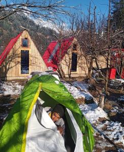 a person sleeping in a tent in the snow at SGM Camp & Cottage in Manāli