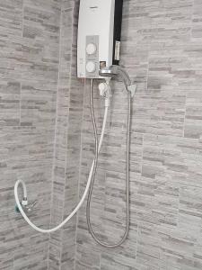 a shower with a hose attached to a wall at Royal Garden Home Hotel in Bangkok