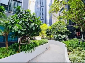 a garden with trees and plants in a city at Asok - Din Daeng Apartment in Bangkok