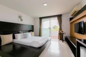 une chambre d'hôtel avec un lit et une télévision dans l'établissement The Mercy Hotel, à Chumpon