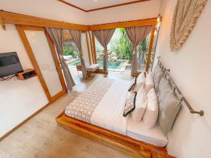 a bedroom with a bed and a tv and some windows at Villa Casa Koko in Gili Islands