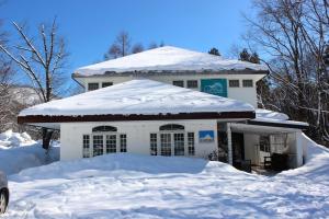 a snow covered house with a pile of snow at Luna Lodge in Hakuba