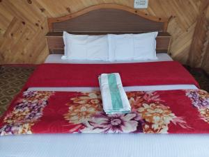 a bedroom with a bed with a red bedspread with a towel on it at Olive Garden Classic in Tosh