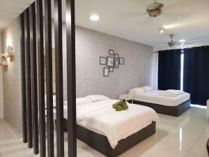 ein Schlafzimmer mit 2 Betten und einem grünen Teddybär auf dem Bett in der Unterkunft Teega Suite - 5 mins from Legoland in Nusajaya