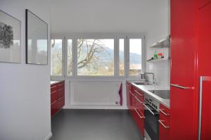 a kitchen with red cabinets and a large window at Haus Noains in Rodels