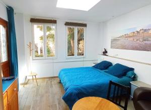una camera con un letto blu e due finestre di MYSaintAubin a Saint-Aubin-sur-Mer