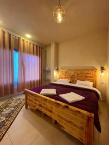 una camera con letto in legno e finestra di Jabal Dana Hotel - the highest hotel in Jordan a Dana