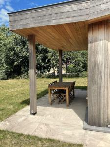 a wooden pavilion with a picnic table in a field at Zeehuis in Koksijde +3 photos