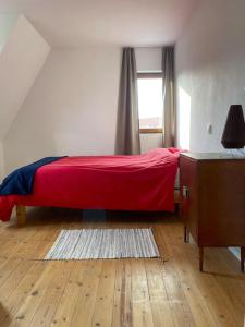 a bedroom with a red bed and a window at Zeehuis in Koksijde