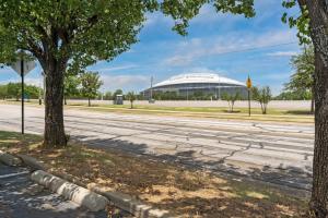 una strada vuota con un grande edificio sullo sfondo di Family Friendly 2bdrm-Walk To At&t/Cowboys Stadium ad Arlington