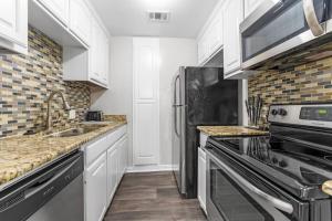 a kitchen with white cabinets and a stainless steel refrigerator at Family Friendly 2bdrm-Walk To At&t/Cowboys Stadium in Arlington