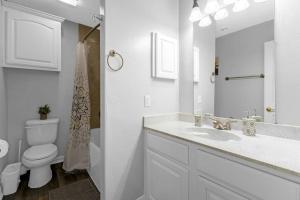 a white bathroom with a toilet and a sink at Family Friendly 2bdrm-Walk To At&t/Cowboys Stadium in Arlington +12 photos