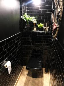 a black tiled bathroom with a black toilet and plants at atelier clermont ferrand historique in Clermont-Ferrand