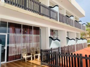 a house with a balcony with chairs and a fence at Yula Beach in Hikkaduwa