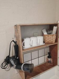 a kitchen shelf with cups and a hair dryer at Guest House ONLY ONE in Niseko