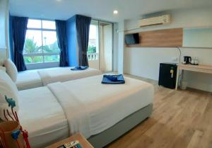a hotel room with two beds and a desk at Karon Living Room - SHA Plus in Karon Beach