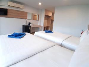 two beds in a room with white sheets and blue pillows at Karon Living Room - SHA Plus in Karon Beach
