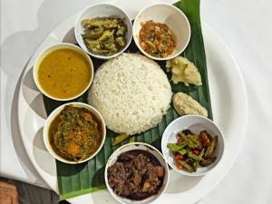a plate of food with rice and different types of food at Assam Villa - by Storyweavers Retreat in Jorhāt